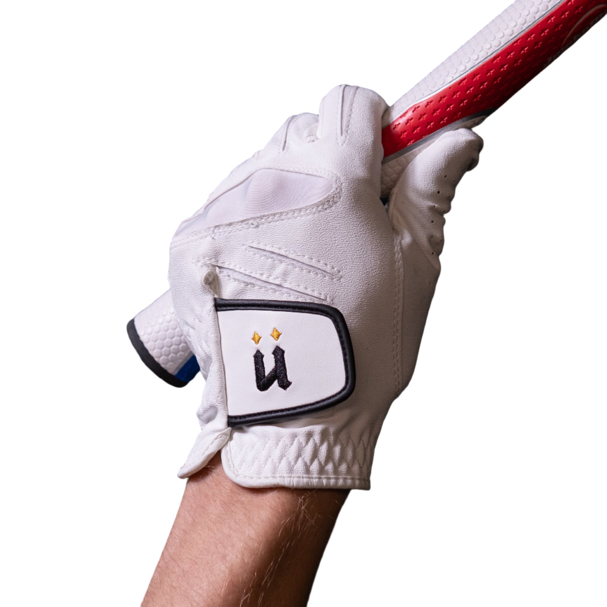 Hand wearing a white golf glove holding a golf club against a dark tiled wall.