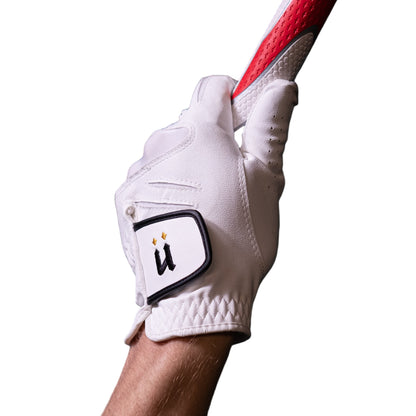 Hand wearing a white golf glove holding a red and white golf club against a dark tiled wall.