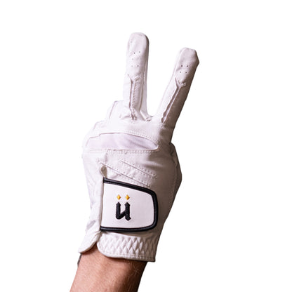 White golf glove with a logo on a hand against a dark tiled wall